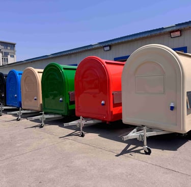 Foodtrucks demi-ronds TF-DM Classic alignés, disponibles dans plusieurs couleurs RAL : noir, bleu, beige, vert et rouge, pers