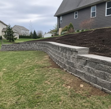 retaining wall installation in Grand Rapids, MI backyard with natural slope by Garcia’s Landscaping 
