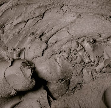 Close-up of thick, textured natural grey clay used for pottery and therapeutic facial masks.