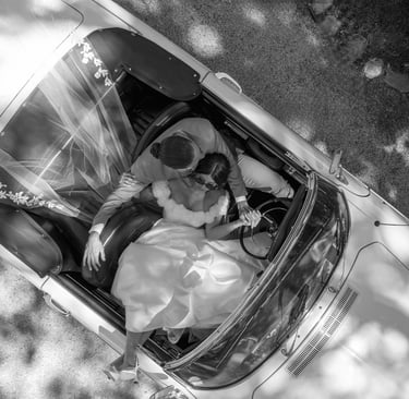Photo éditoriale en noir et blanc de mariés dans une voiture de collection, chic & cinématographique