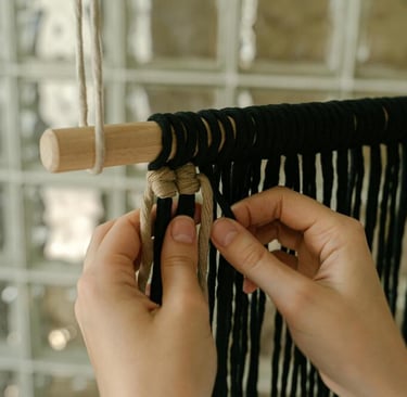 manos creando un adorno tejido de macramé negro y gris