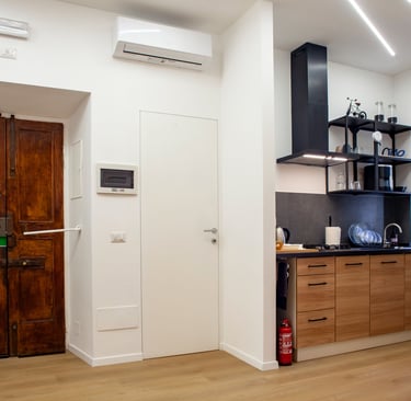 Modern studio apartment featuring a rustic wooden door and a sleek kitchen with wood cabinets.