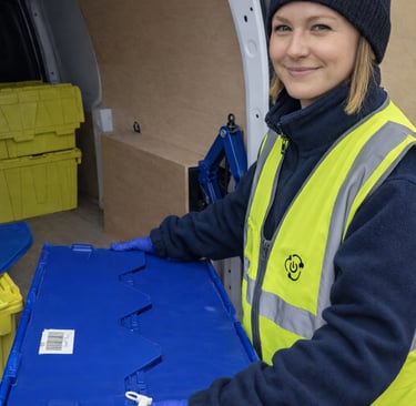 A close up of a TTB employee carrying a sealed crate of electricals to our electric van