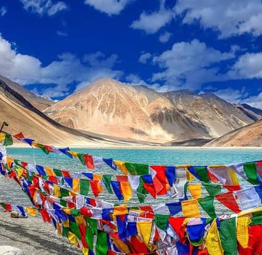 Colorful Buddhist prayer flags fluttering by the turquoise Pangong Lake in the Ladakh Himalayas.