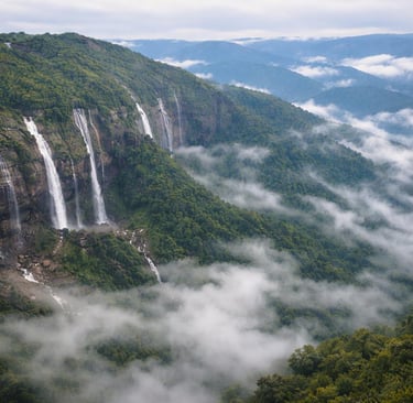 Panoramic view of the Seven Sisters Waterfalls in Meghalaya falling from lush green cliffs into a misty valley.