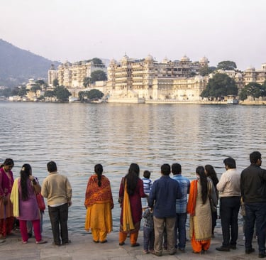 Tourists viewing the historic Udaipur City Palace across Lake Pichola in Rajasthan, India.
