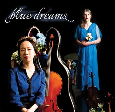 two people in blue with a black backdrop. The person in the front has a cello next two them.  