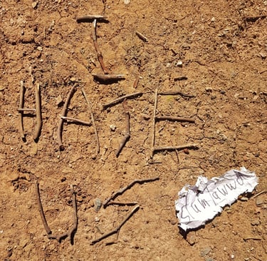 the words I hate us written in sticks on a brown gravel ground