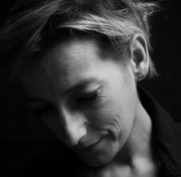 Black and white portrait of a woman with short hair looking down in deep thought.