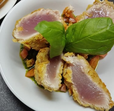 Tagliata di tonno pinna gialla scottata in crosta servita con pomodorini e basilico fresco.