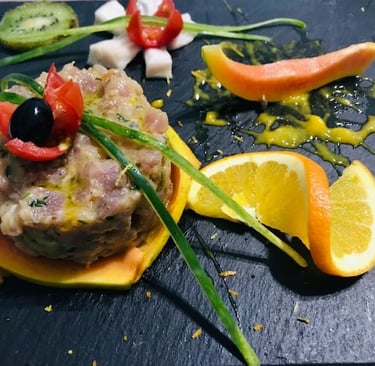 Elegante composizione di tartare di tonno con fettine di arancia, melograno e decorazioni di verdure