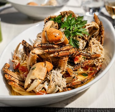 Piatto generoso di pasta con granchi freschi e pomodorini, specialità di mare del ristorante a Vila 