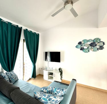 Modern living room with teal curtains, a blue sofa, fish wall decor, and a ceiling fan.