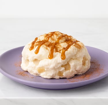 A high protein, creamy dessert pudding topped with caramel sauce and cinnamon on a purple plate.