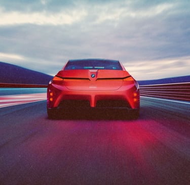 Rear view of a red BMW concept electric car driving on a high-speed racetrack at dusk.