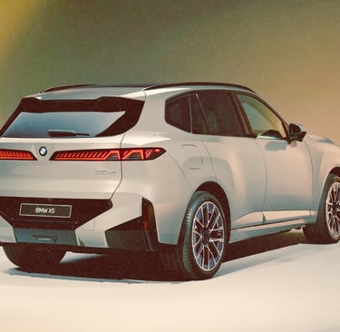 Rear three-quarter view of a silver BMW X5 luxury SUV in a studio with bright lighting.