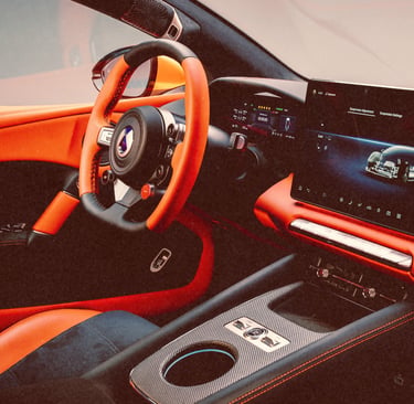 Luxury sports car interior featuring orange leather upholstery, carbon fiber trim, and a digital infotainment screen.