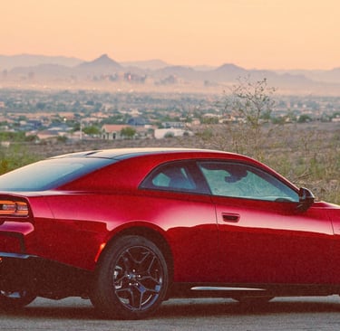 A red Dodge Charger Daytona electric muscle car parked on a mountain overlook at sunset.