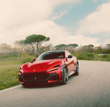 A red Ferrari Purosangue performance SUV driving fast on a scenic winding road through a green landscape.