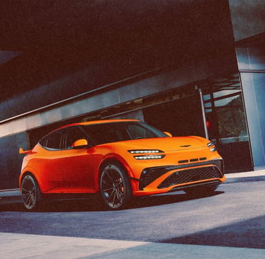 A bright orange Genesis GV60 Magma concept electric SUV parked in front of a modern building.