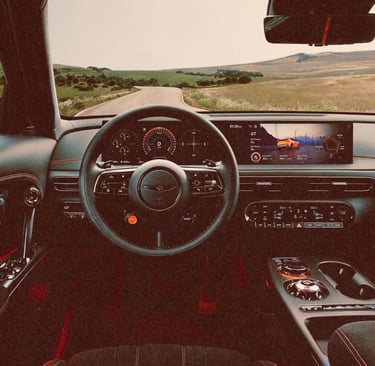 Modern luxury car interior with a digital dashboard and steering wheel overlooking a scenic road.