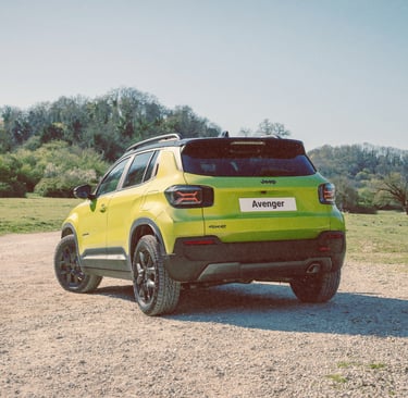 A lime green Jeep Avenger 4xe compact SUV parked on a gravel path in a sunny outdoor countryside setting.