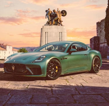 A green Maserati GranTurismo parked in a scenic Italian plaza with a stone statue at sunset.