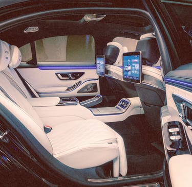 Luxury car interior featuring white leather seats, ambient lighting, and rear seat entertainment screens.