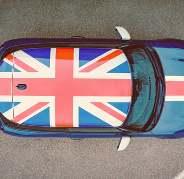 Aerial view of a blue Mini Cooper featuring a Union Jack flag roof decal parked on asphalt.