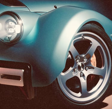 Close-up of a blue Morgan Supersport luxury sports car with glowing LED headlights and alloy wheels.