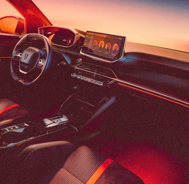 Modern car interior with digital dashboard and touchscreen display illuminated by orange sunset light.