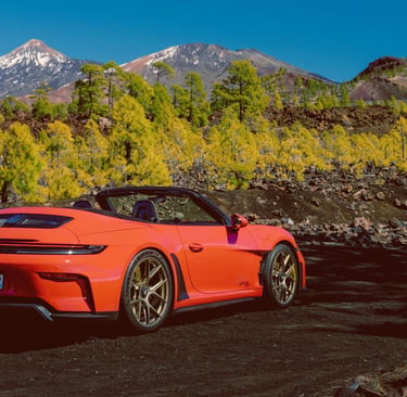 Red Porsche 911 GT3 S/C parked on a volcanic landscape with mountains in the background.
