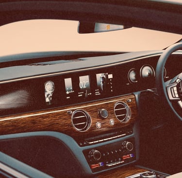 Luxury interior of a Rolls-Royce Spectre showing the wood dashboard, digital display, and steering wheel.