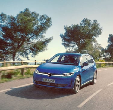 Blue Volkswagen ID. Polo electric car driving on a scenic winding road with trees.