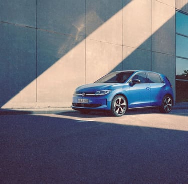 A blue Volkswagen ID. Polo parked in front of a modern concrete building with sunlight and shadows.