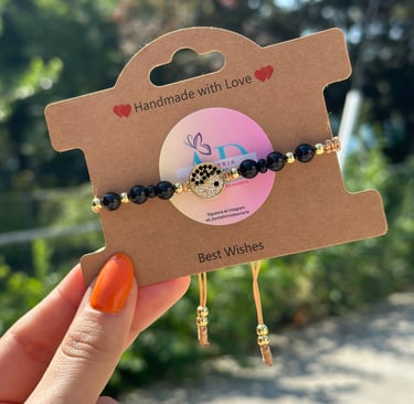 pulsera de perlas negras con cordon cafe y terminado en perlas doradas