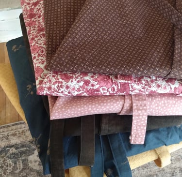A stack of neatly folded wrap skirts made with love from assorted pretty cotton calico fabrics