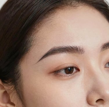 Nila carefully threading a client's eyebrow with focused attention and care.