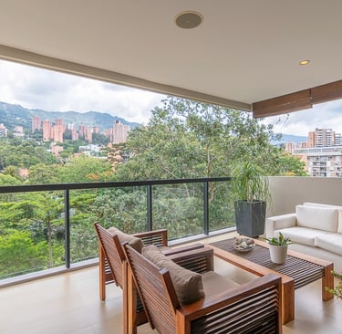 Modern luxury apartment balcony with wooden patio furniture and a scenic mountain city view.