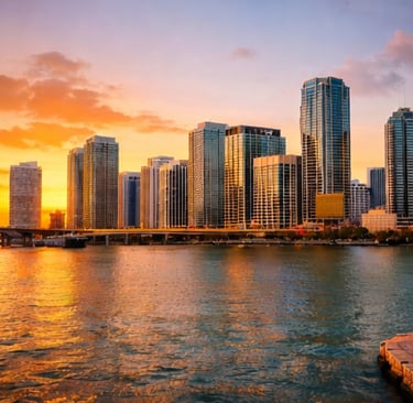 Golden sunset over the Miami skyline skyscrapers and waterfront with a bridge and palm trees.