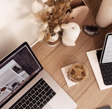 Aesthetic home office desk with laptop, iced coffee, dried flowers, and productivity planner.