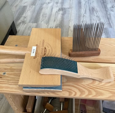 Wool carders and a comb on a wooden bench