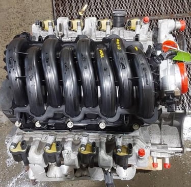 High-performance V8 car engine with black intake manifold and silver block in an auto repair shop.