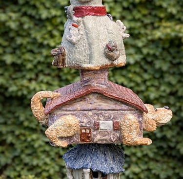 A vertical ceramic totem pole featuring a stack of various dog breeds accented with vibrant glazes.