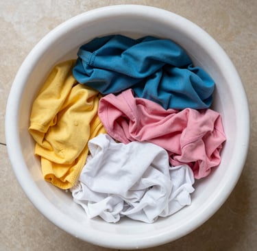 Hands gently washing a white lab coat in a basin with mild detergent.
