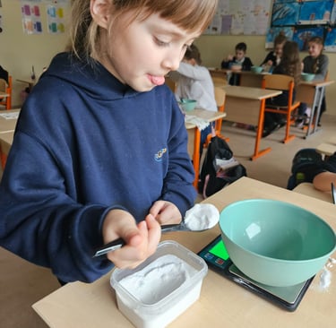 Mergaitė susikaupusi sveria medžiagas STEAM eksperimentui