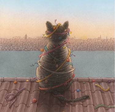 A gray tabby cat wrapped in colorful ribbons sits on a roof overlooking a city skyline at sunset.