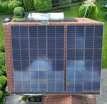 High-angle aerial view of a residential rooftop with a large solar panel array installed for renewable energy.