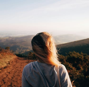 Eine Frau überblickt eine weite Landschaft im Morgenlicht