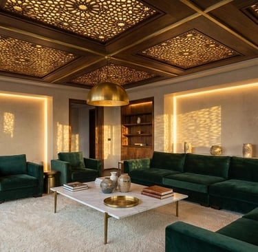 Modern luxury living room featuring green velvet sofas and intricate carved wood ceiling panels with gold accents.